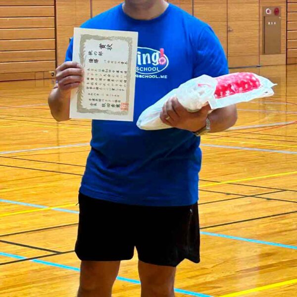 Atleta de tenis de mesa da Spring School segurando em sua mão direita o certificado de campeão do campeonato.