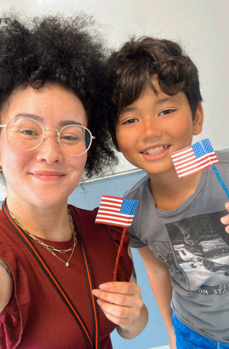 Professora e aluno pousando para a selfie com as bandeiras dos EUS em mãos celebrando o 4th of july - dia da independência americana.