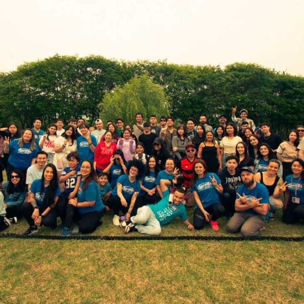 Alunos e Equipe Spring School pousando para foto em belo jardim gramado e com árvores ao fundo.