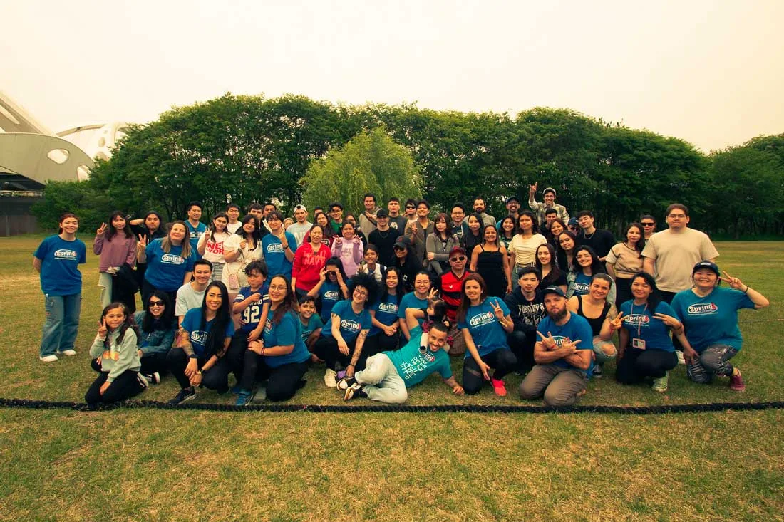 Alunos e Equipe Spring School pousando para foto em belo jardim gramado e com árvores ao fundo.