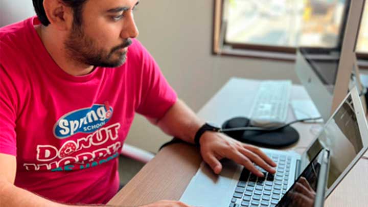 Professor da Spring School mexendo em seu computador no escritório.