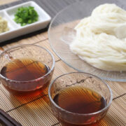 Imagem contendo um prato principal com lamén e outras duas tigelas com molho de soja.